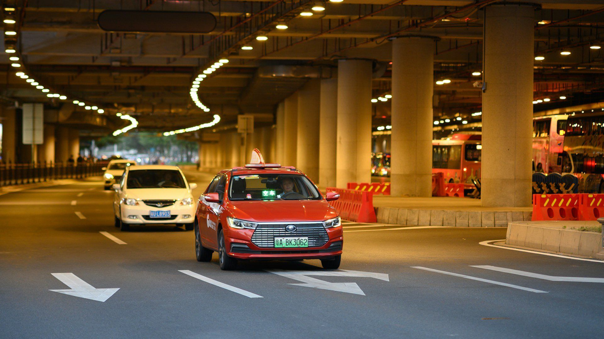 Yango driver standing beside a white Suzuki Alto with red Yango branding in Islamabad at night
